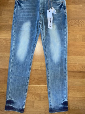 Blå skinny jeans från Purple - Säljer ett par blå skinny jeans från Purple med snyggt slitna detaljer och ljusa tvättade partier. Jeansen har klassisk femficksdesign och är tillverkade i mjukt denimtyg med stretch för extra komfort. Perfekta för en trendig och avslappnad look.