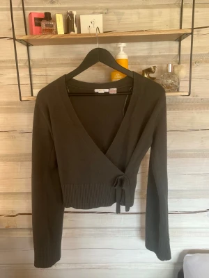 Mörkgrön kofta  - Mörkgrön stickad kofta med ihopsydd rosett på sidan, använd fåtalet gånger