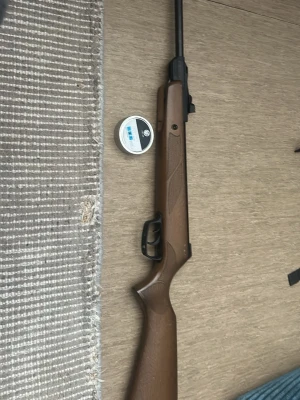 Luftgevär med trästock - Säljer ett luftgevär med klassisk brun trästock och svart pipa. Geväret har ett enkelt sikte och medföljer en burk luftgevärskulor. Perfekt för dig som gillar skytte på fritiden.