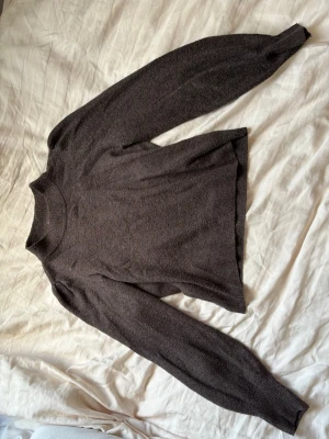 Mörkbrun stickad tröja - Mysig mörkbrun stickad tröja med rund halsringning och långa ärmar. Använd fåtal gånger 🥰.Tröjan har en enkel, rak passform och ribbstickade muddar vid ärmslut och hals. Riktigt snygg tröja!