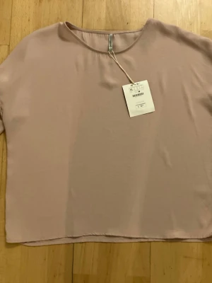 NY Ljusrosa topp från Stradivarius storlek XL - Enkel och stilren ljusrosa topp från Stradivarius. Toppen har rund halsringning, korta ärmar och rak passform. Tillverkad i ett mjukt och lätt material som känns skönt mot huden. Perfekt att matcha med jeans eller kjol.