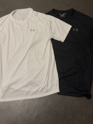 Under Armour Tech T-shirt 2-pack - 225kr styck. Två sportiga t-shirts från Under Armour i modellen Tech Tee. Ena är vit och den andra svart, båda med diskret logga på bröstet. Tillverkade i ett lätt och snabbtorkande funktionsmaterial som passar perfekt till träning eller gym.