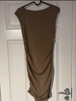 Brun draperad klänning med öppen rygg - brun klänning med snygg drapering som framhäver figuren på ett smickrande sätt. Ärmlös design med öppen rygg som ger en elegant och självsäker look. En perfekt klänning för fest, utekväll eller när du vill känna dig extra snygg 💫(ifrån shein) 