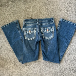 Blå bootcut jeans från Gina Tricot - Säljer ett par klassiska blå jeans från Gina Tricot i modell bootcut. Jeansen har fem fickor, snygga kontrastsömmar och dekorativa ficklock bak med knappdetalj. Defekter på de två sista bilderna. Men syns knappt! Användt ungefär 2 gånger i skolan. Skriv privat om du har frågor! Midjemåttet är 35 rakt över💕