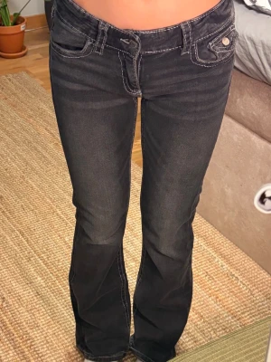 Svarta bootcut jeans med kontrastsömmar🌸 - Snygga svarta bootcut jeans med vita kontrastsömmar och klassiska fem fickor. Jeansen har låg midja och utsvängda ben, vilket ger en retro vibe. 