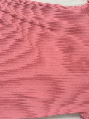 Rosa ribbad kjol - En rosa ribbad kjol med stretchigt tyg och enkel design. Kjolen har en mjuk struktur och passar perfekt till en avslappnad eller trendig outfit. Färgen är en fin rosa ton och materialet känns bekvämt mot huden.