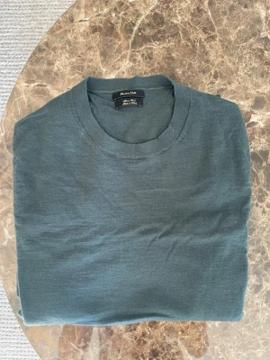 Mörkgrön stickad merinoull tröja Massimo Dutti  - Mörkgrön stickad tröja från Massimo Dutti med rund halsringning. Tröjan har en enkel och stilren design, perfekt för lager på lager. Tillverkad i mjukt material som känns skönt mot huden.
