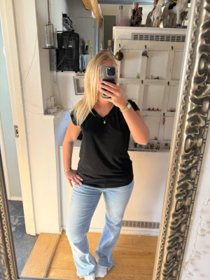 Svart v-ringad ärmlös topp - En enkel svart topp med v-ringning och ärmlös design. Tillverkad i mjukt bomullstyg som känns skönt mot huden. Perfekt att matcha med jeans eller kjol för en clean och avslappnad look.