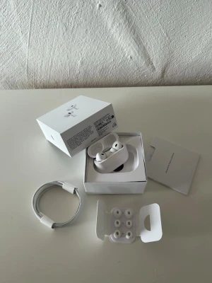 Apple AirPods Pro 2 vita - Säljer ett par helt nya, oanvända Apple AirPods Pro (andra generationen) i vitt. Inkluderar laddnare, USB-C kabel och extra silikonpluggar i olika storlekar. Snygg och kompakt design med mjuka former och högkvalitativt plastmaterial. Perfekta för musik, poddar och samtal. Fick i present och säljer då jag redan hade ett par