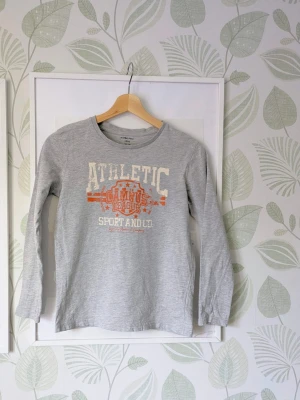 Långärmad Tshirt Ellos Storlek 146/152 - - I fint skick.  - Lantligt tryck som ska se lite slitet ut men jag vet inte om mer tillkommit pga användning.  - Sömmar i armar har flyttat sig så de sitter lite snett ju längre ner mot handen sömnen går förutom detta så är tröjan jättefin.  - Jag kan ha missat någon miniskavank men jag har försökt att granska plagget så gott det går.