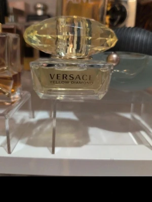 Versace Yellow Diamond parfym 50ml - Versace Yellow Diamond är en elegant parfym i en lyxig, transparent glasflaska med guldfärgad vätska och en stor, diamantformad gul kork. Flaskan rymmer 50 ml och har en exklusiv känsla som passar perfekt för dig som gillar stilrena och glamorösa dofter.
