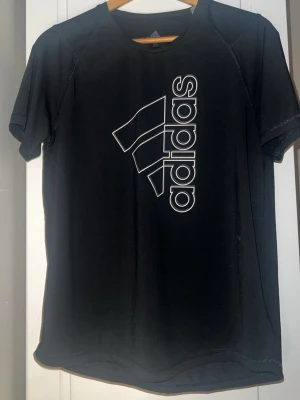 Svart tränings-tshirt från Adidas - Snygg svart tränings-tshirt från Adidas med stort vitt logotryck på framsidan. Det är storlek M men jag tycker den passar bra om man vill ha en mer baggy look👀