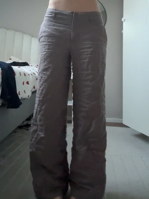 Vida linnebyxor i gråbrun ton - Säljer ett par snygga vida linnebyxor i en gråbrun färg. Byxorna har medel midja, raka ben och stängs med dragkedja och knapp. Perfekta för en chill och avslappnad stil. Materialet är 100% linne vilket gör dem luftiga och bekväma.