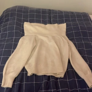 Vit stickad polotröja - Säljer en vit stickad polotröja med bred krage och långa ärmar. Tröjan har ribbstickade muddar vid ärmslut och nederkant, vilket ger en snygg och bekväm passform. Perfekt för att hålla värmen under kyliga dagar.