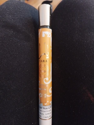 Yara Eau de Parfum spray - En smal och elegant parfymflaska från Yara med guldfärgad och vit design samt silverfärgat lock. Flaskan är cylinderformad och rymmer 35 ml (1.18 fl oz). Perfekt att ha med i väskan för en fräsch doft när som helst.