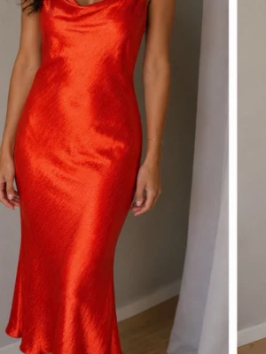 Orange långklänning med tunna band strl 40 - Snygg orange långklänning med tunna reglerbara axelband och lätt draperad urringning. En snygg djup urringning baktill .Klänningen har en slank passform och är tillverkad i ett glansigt material som ger en lyxig känsla. Perfekt för dig som vill sticka ut med färg och stil. Prislapp ej kvar i men helt ny aldrig använd 