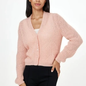 Rosa kofta i mohair /mohairblandning från Indiska 38/40 - Stickad kort söt kofta. Koftan har långa ärmar, en v-ringad hals. knappar framtill och ett vackert hålmönster. Helt ny med alla lappar kvar, storlek M (38/40)  Material: 40 % Akryl, 30 % Mohair, 30 % Nylon