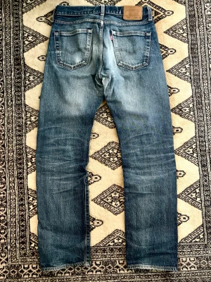Levi's 501 blå raka jeans - Jag säljer dessa otroligt snygga vintage Levi’s 501-jeans i storlek 30 × 32. De har en riktigt cool tvätt och är i fantastiskt bra kvalitet.  Lägg ett bud om du är intresserad, så kanske vi kan komma överens om något.  * Midja: 40 cm * Längd: 104 cm * Benöppning: 19 cm  Skriv gärna om du har några frågor! :)