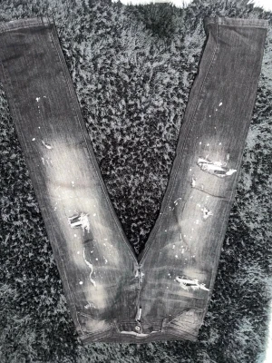 Grå slitna jeans med färgstänk - Säljer ett par grå jeans med coola slitningar och vita färgstänk. Jeansen har en smal passform och klassisk femficksdesign. Perfekta för dig som gillar en edgy och trendig stil.