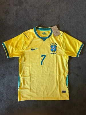 Brasilien VM 26/27 hemma Vini JR 7 - Fotbollströja med Vini JR på ryggen. Tröjan är helt ny med tagg kvar och i perfekt skick. Storlek M. Perfekt för dig som är supporter, samlar på fotbollströjor eller vill ha en snygg tröja till träning och vardag. 🟨 Storlek M 🟨 Helt ny med tagg 🟨 Vini JR 🟨 Skickas inom 24 timmar Vid intresse eller frågor är det bara att skicka 👍