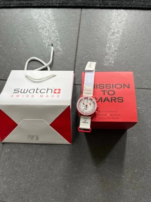 Omega x Swatch Speedmaster Mission to Mars - Säljer en Omega x Swatch Speedmaster Mission to Mars MoonSwatch. Klockan har vit rem och urtavla med röda detaljer och boett. Kommer med originalförpackning och påse. En riktigt snygg och unik klocka för dig som gillar cool design. (Rep)