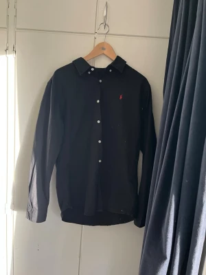 Polo Ralph lauren skjorta  - Säljer en Ralph lauren skjorta i svart. Skjortan är oanvänd så skicket är som nytt. Hör av dig vid funderingar 🙃passar M/L