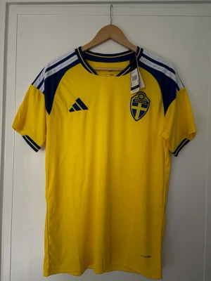 Sverige vm  hemma tröja storlek L - 🇸🇪 Sverige Hemmatröja – Strl L 🇸🇪  Säljer en snygg Sverige hemmatröja i klassisk gul design med blå detaljer. Perfekt för fotbollsintresserade eller dig som gillar sportiga outfits.  ✨ Ny med tags 📏 Storlek L ⚽ Bekväm passform 🔥 Stilren design med fina detaljer 👕 Passar både till vardags och matchdagar  Skick: Oanvänd  💰 Pris: 299 kr  📦 Skickas snabbt och välpaketerat!.  Hör gärna av dig om du har frågor eller vill se fler bilder