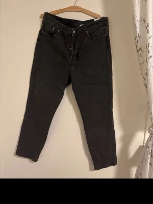 Mörkgråa raka jeans  - Säljer ett par mörkgråa jeans med rak passform och klassisk femficksdesign. Jeansen har knappgylf och är tillverkade i ett slitstarkt material