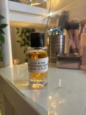 Parfym lukt liknade marshmallow  - En stilren parfymflaska i glas med svart lock från The Perfume Brand. Flaskan rymmer 50 ml och innehåller en bärnstensfärgad Eau de Parfum, E.D.P. No 058. Perfekt för dig som gillar minimalistisk design och exklusiva dofter.