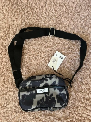 Mönstrad axelväska från DAY ET - Köptes för några år sen så den går inte att köpa längre. Helt ny med lappar. Nypris 569kr. Aldrig använd.