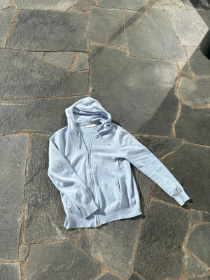 Ljusblå zip hoodie - Snygg ljusblå hoodie från sayless med dragkedja framtill och två fickor. Tillverkad i mjukt material och har justerbar huva med snören. Perfekt för en chill och avslappnad stil.
