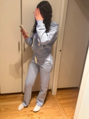 Nytt Ljusblått mjukisset med huva från Gina tricot strl S slutsåld  - Säljer ett ljusblått mjukisset med dragkedja och huva. Setet består av en hoodie med vita snören och matchande byxor med resår i midjan och vita detaljer. Perfekt för chill dagar hemma eller när du vill vara bekväm.