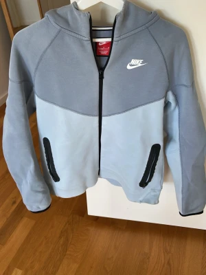 Nike ljusblå hoodie med dragkedja - Nike tech houdie ljusblå. Några få repor som kanske syns på bilderna men inte när man har på den. 158-170cm. 