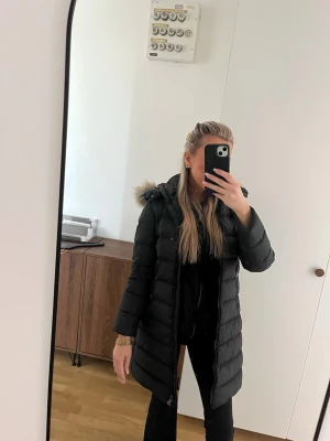 Moncler jacka  - Säljer en svart lång dunjacka från Moncler. Jackan har en figurnära passform, quiltad design och dragkedja framtill. Perfekt för kalla vinterdagar och riktigt snygg till alla outfits. Passa på att köpa vinterjacka för billigt pris. Låda, kvitto medföljer 
