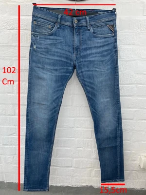 Replay jeans  - Snygga blå slim fit jeans med lätt slitna detaljer och dragkedja på fickan fram. Klassisk femficksmodell med smal passform och normalhög midja. Jeansen har måtten 102 cm i längd, 42 cm i midja och 15,5 cm vid benslut. Perfekta för en trendig och avslappnad stil.