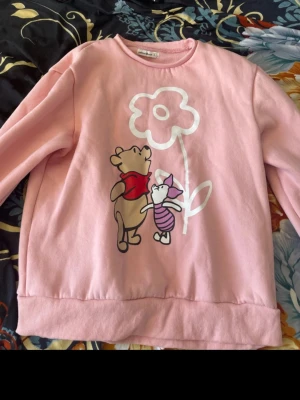 Rosa tröja med Nalle Puh - Söt rosa tröja med tryck av Nalle Puh och Nasse. Endast använd ett fåtal gånger. Perfekt för dig som gillar gulliga och lekfulla motiv.