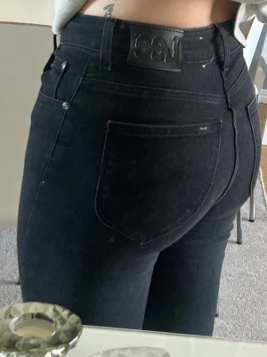 Svarta bootcut jeans från Lee - Snygga svarta bootcut jeans från Lee med klassisk femficksdesign och hög midja. Jeansen har en diskret Lee-logga på bakfickan och är tillverkade i ett stretchigt denimtyg som sitter bekvämt och formar sig efter kroppen. Storlek : W27 L31 ( xs/s)  original pris 999 kronor. 