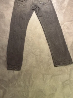 Grå raka jeans från replay - Snygga grå jeans från replay med raka ben och klassiska bakfickor. Jeansen har en avslappnad passform och är tillverkade i mjukt denimtyg. Perfekta för en casual look och lätta att matcha med olika stilar.