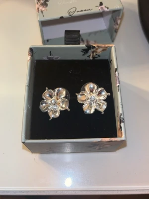 IOAKU örhängen  - Säljer ett par silvriga la fleur örhängen ifrån IOAKU!! I super fint skick endast använda 1 gång!