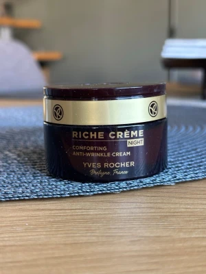 Yves Rocher Riche Crème nattkräm - Lyxig nattkräm mot rynkor från Yves Rocher, Riche Crème. Kommer i en mörkbrun rund burk med guldfärgat lock och detaljer. Innehåller 50 ml och är tillverkad i Frankrike. Perfekt för dig som vill ha extra vårdande hudvård på natten.
