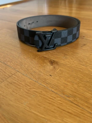 ZARA bälte svart - Snyggt svart bälte från ZARA med klassiskt rutigt mönster och logga i metall framtill. Bältet är gjort i skinn och har en stilren design som passar till många olika outfits.