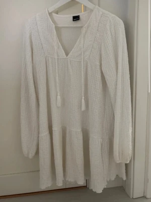 Vit långärmad boho-klänning - Superfin vit klänning från Gina Tricot i boho-stil med lång ärm, v-ringning och knytband. Använd endast 2 gånger💕💕klänningen har en lös passform