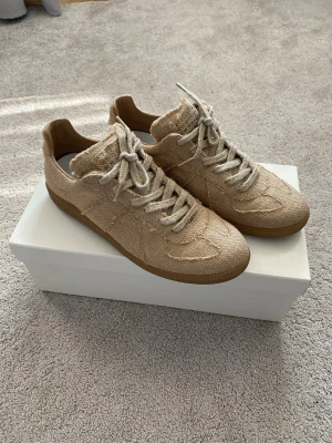 Maison Margiela Linen/Canvas Gats - Snygga Maison Margiela beige sneakers i grovt tygmaterial med matchande skosnören och klassisk gummisula. Skorna har en låg profil och stilren design som passar till det mesta. Perfekta för dig som gillar en clean och avslappnad look.