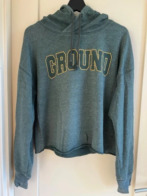 Grön hoodie med tryck - Mysig grön hoodie med huva och snören.  Köpt på lager 157.
