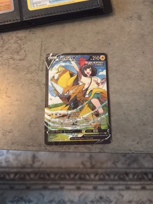 Pokémonkort Zeraora V Rapid Strike - Säljer ett Pokémonkort med Zeraora V Rapid Strike-motiv. Kortet har färgstark design med Zeraora och en tränare i bakgrunden. Det är ett samlarkort med holografiska detaljer och tydliga stats. Perfekt för dig som gillar Pokémon och samlarkort. Pris kan diskuteras 