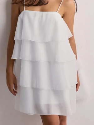 Vit volangklänning - Säljer en superfin vit kortklänning med flera lager volanger och tunna axelband. Klänningen har en luftig och flowy känsla, perfekt för sommaren