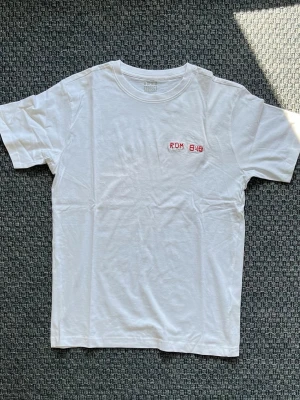 Handbroderad vit t-shirt från Denim Project - Vit t-shirt från Denim Project med handbroderad text 'ROM 8:18' i rött på bröstet. Finns knappt synlig smuts på framsidan. 