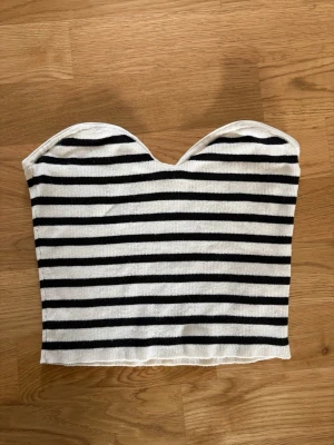 Randig bandeau tubtopp i bomull - Säljer en snygg bandeau tubtopp med svarta och vita ränder. Toppen är ärmlös och har en hjärtformad överkant, storlek XS