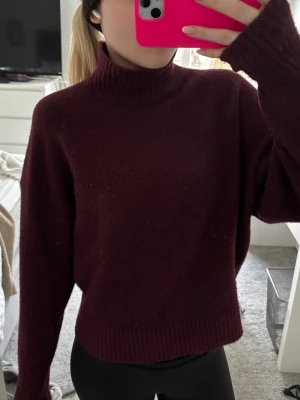 Vinröd stickad polotröja från Zara - Mysig vinröd stickad polotröja från Zara med krage och långa ärmar. Tröjan har en avslappnad passform och ribbade muddar vid ärmslut och nederkant. Perfekt för kalla dagar och enkel att styla med jeans eller jeanskjol!🥰