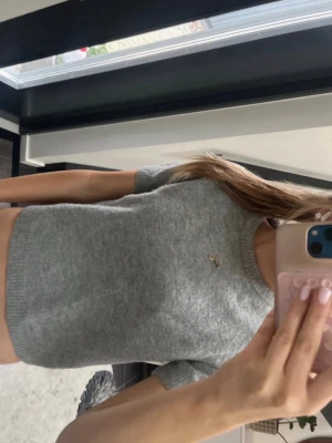 Grå stickad kortärmad tröja Zara - Säljer en grå stickad kortärmad tröja från Zara. Tröjan har rund halsringning, ribbade kanter och en liten gulddetalj på bröstet. Perfekt till jeans eller kjol för en enkel och snygg look.